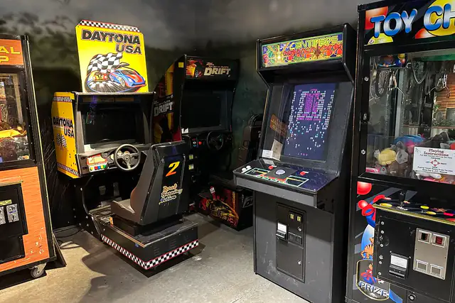 A row of colourful arcade cabinets including a driving game