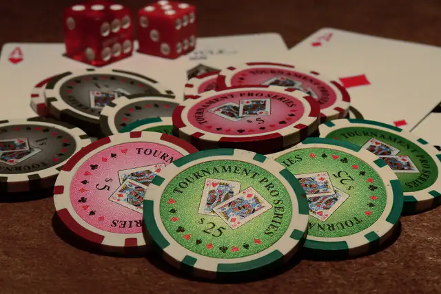 Tournament poker chips and red dice spread across playing cards