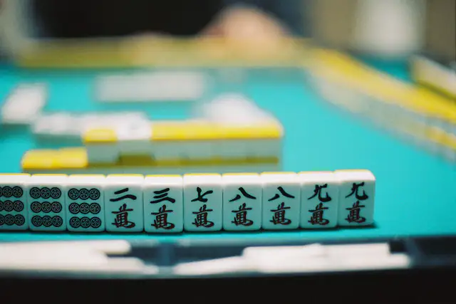 A row of mahjong tiles standing on a green table