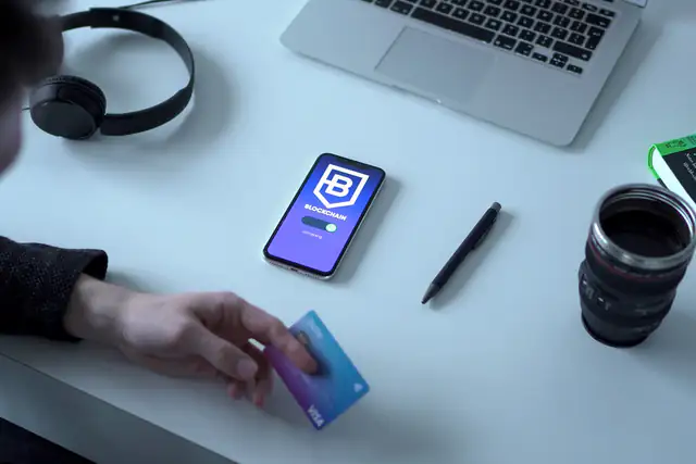 Person holding a payment card next to a smartphone showing a connecting screen